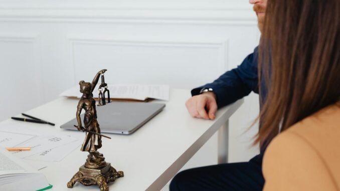droit des affaires Cadre professionnel avec des avocats et une statue de Lady Justice discutant de documents juridiques.