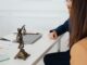 Cadre professionnel avec des avocats et une statue de Lady Justice discutant de documents juridiques.