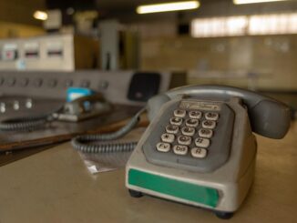 Ancienne machine à écrire grisâtre sur un bureau, clavier et câble visibles