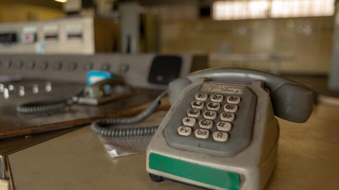 Ancienne machine à écrire grisâtre sur un bureau, clavier et câble visibles