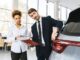 Professionnels examinent un véhicule dans un showroom lumineux