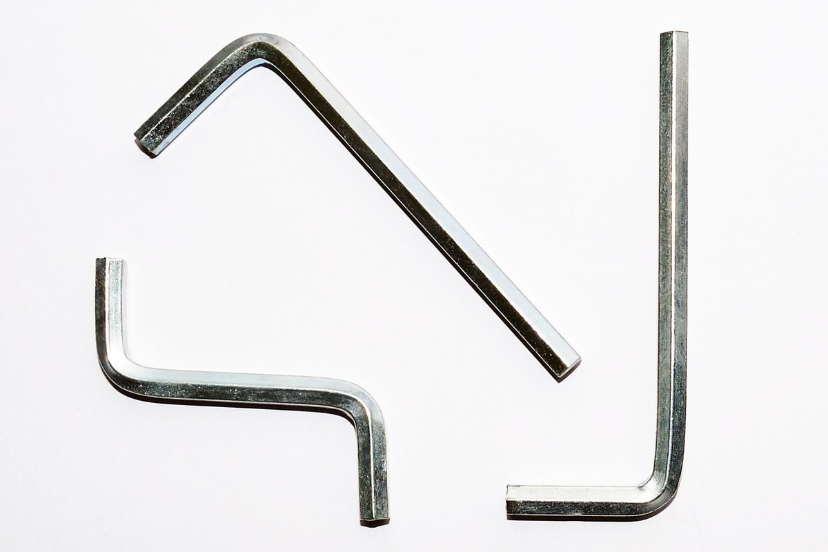 Trois barres métalliques en forme de L et de N sur fond blanc