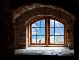 Fenêtre à guillotine en bois dans un mur de briques, vue extérieure avec ciel bleu et nuages