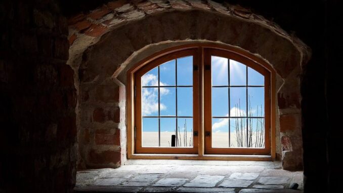 Fenêtre à guillotine en bois dans un mur de briques, vue extérieure avec ciel bleu et nuages